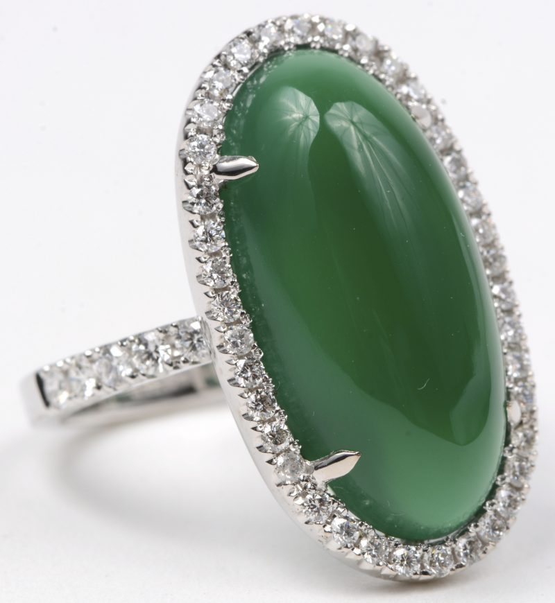 Een 18 karaats wit gouden ring bezet met briljanten met een gezamenlijk gewicht van ± 0,53 ct. en een cabochon van jade van ± 8,04 ct.
