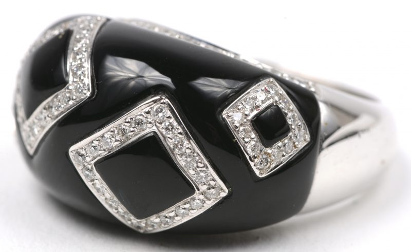 Een 18 karaats wit gouden ring bezet met briljanten met een gezamenlijk gewicht van ± 0,68 ct. en onyx.