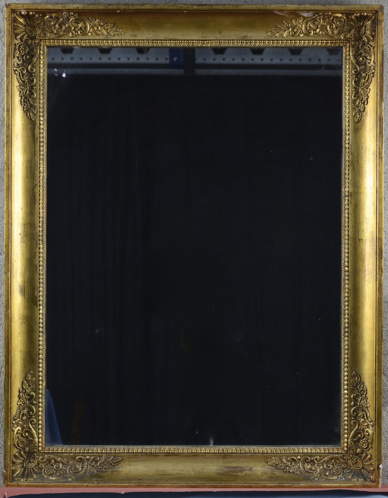 Een rechthoekige spiegel in goudgepatineerde houten lijst.
