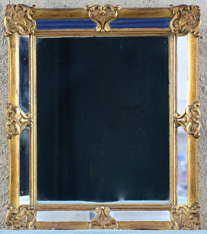 Een spiegeltje in goudgepatineerde houten lijst.