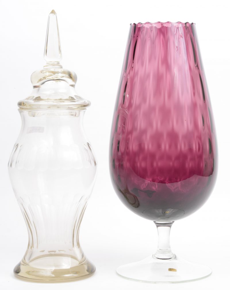 Een grote kristallen vaas op voet met purperen kelk en een kleurloze dekselvaas.