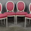 Een reeks van acht witgepatineerde stoelen in Lodewijk XVI-stijl met roze bekleding.