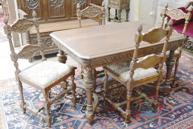 Een gebeeldhouwde tafel in renaissancestijl met vier stoelen in gelijkaardige stijl.