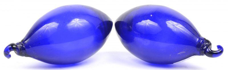 Twee druppelvormige hangornamenten van blauw glas.