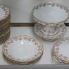 Een eetservies van Limogesporselein met een rozendecor met vergulde rocaillerand. Patent Porcelaine-Mousseline. Onderaan gemerkt.