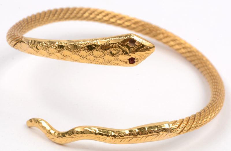Een 18 karaats geel gouden armband in de vorm van een slang bezet met één robijntje, één ontbreekt.
