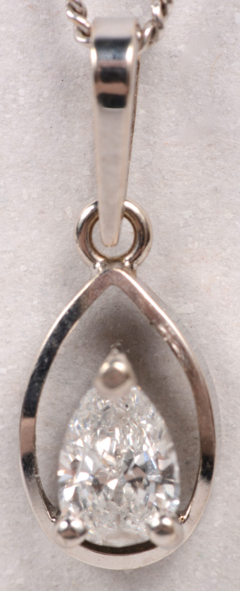 Een 18 karaats wit gouden ketting met hanger bezet met een diamant in peerslijp van +/- 0,30 ct.
