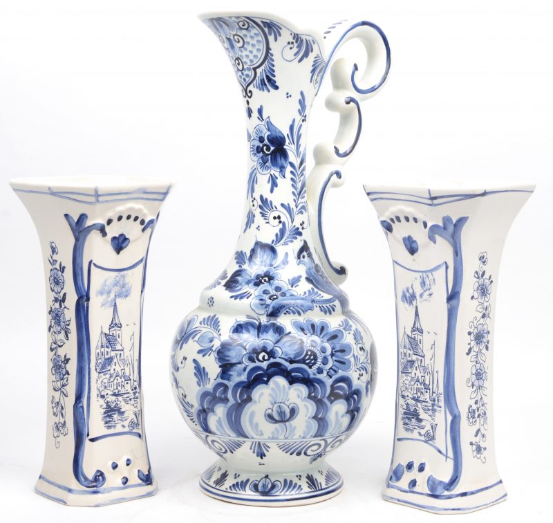Een blauw en witte Delftse schenkkan en twee hoornvaasjes van Hollands aardewerk in Delftse stijl.