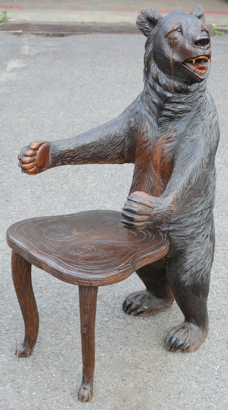 Een gebeeldhouwde houten stoel met de rug en leuningen in de vorm van een staande beer. Zwarte woud. Gebarsten.
