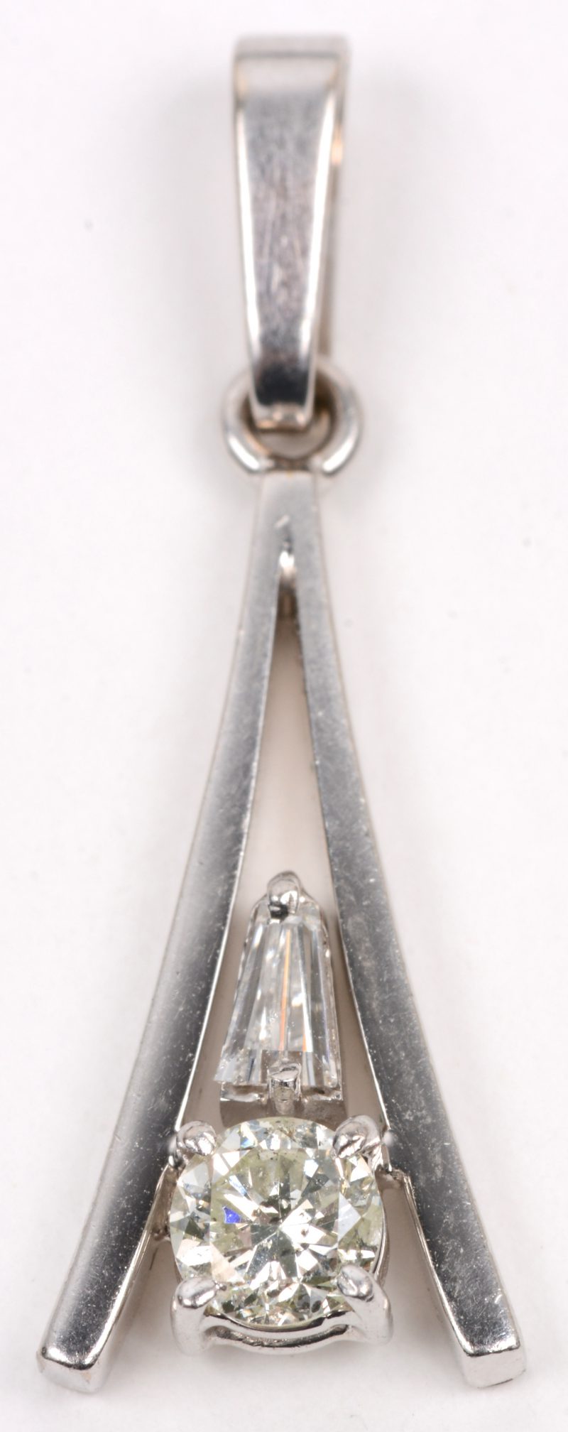 Een 18 karaats wit gouden hanger bezet met een diamant van +/- 0,35 ct. en een diamantbaguet van +/- 0,10 ct.
