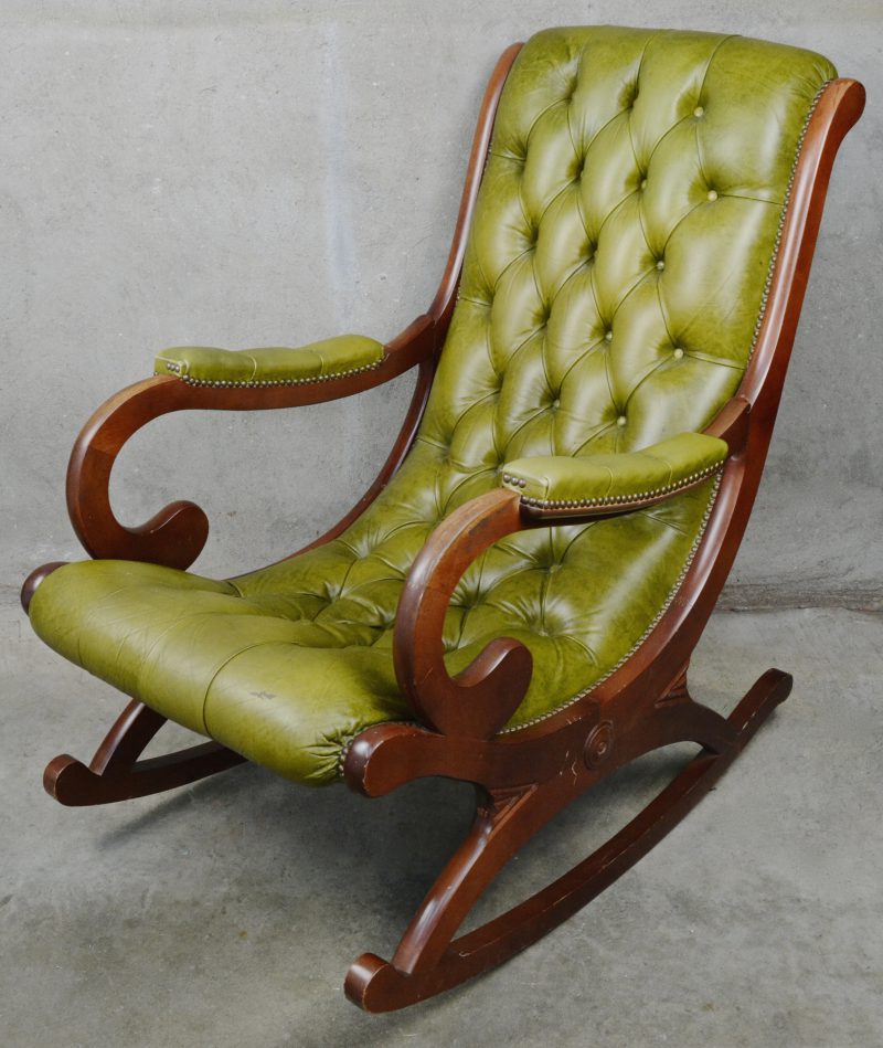 Een Engelse schommelstoel, bekleed met gacapitoneerd groen leder.