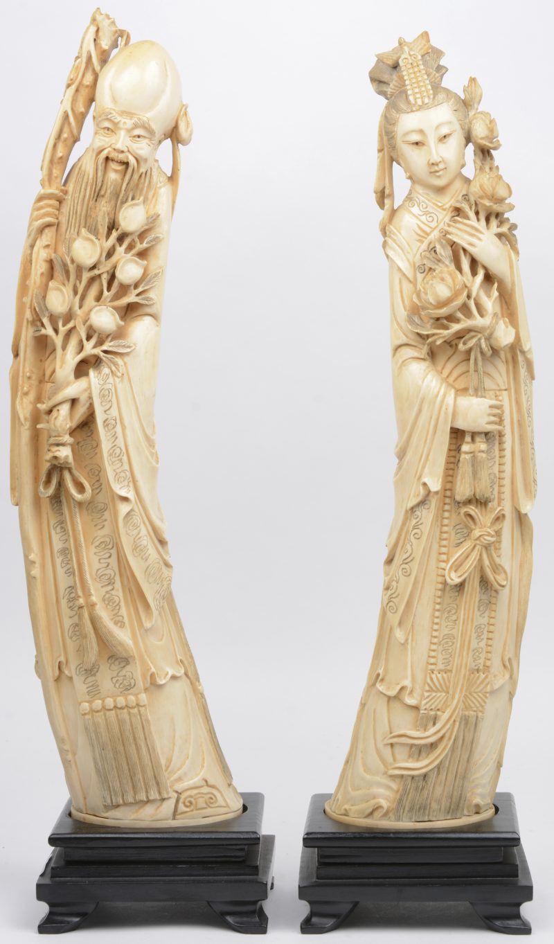 Een wijze en een dame van fijn gesculpteerd Chinees ivoor. Op houten voetstukkken. Omstreeks 1900.