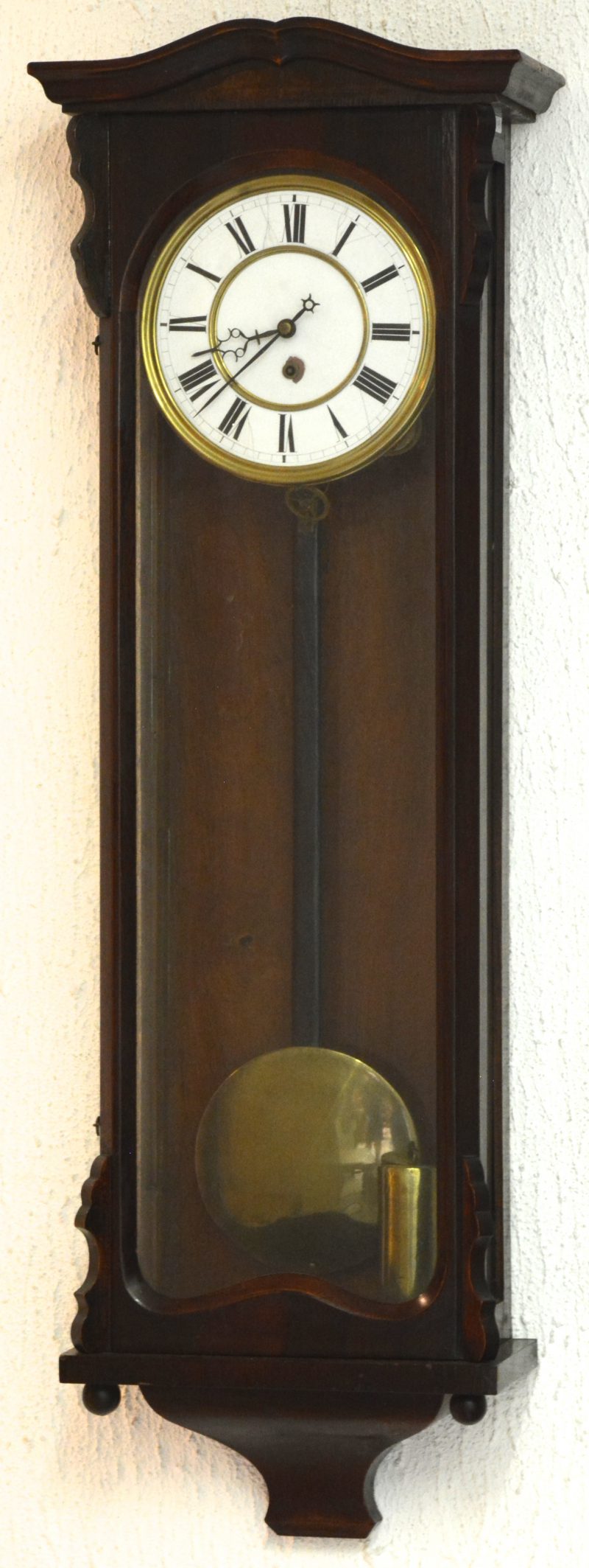 Een regulateur in houten kast. Met slinger en sleutel.