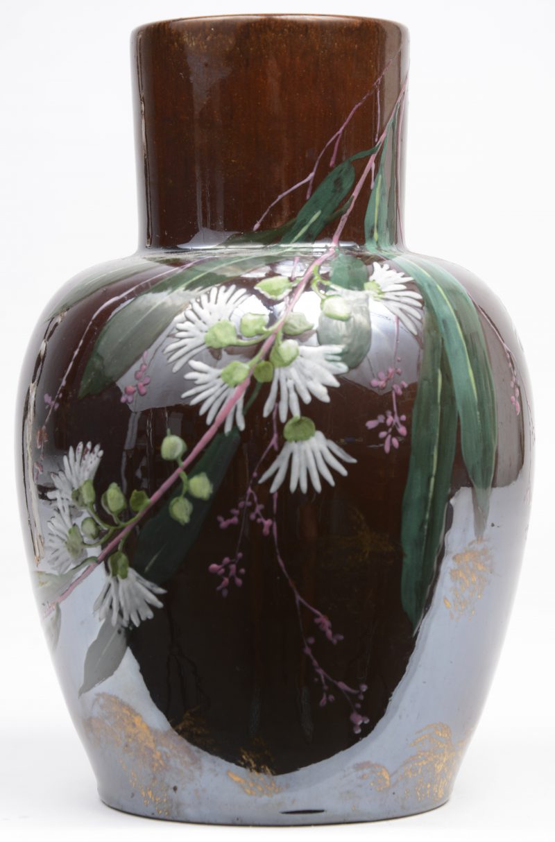 Een aardewerken vaasje met een handgeschilderd plantendecor en een iriserend glazuur.
