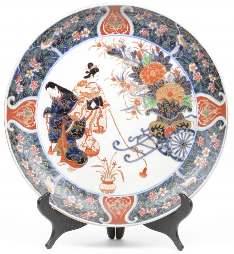 Een bord van Imariporselein met een decor van twee geisha’s bij een bloemenkar in het plat.