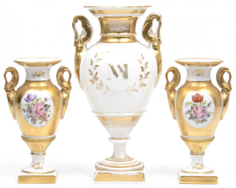 Drie siervaasjes van deels verguld Brussels porselein, waarbij twee een paar vormen en versierd zijn met een meerkleurig bloemendecor. XIXe eeuw.