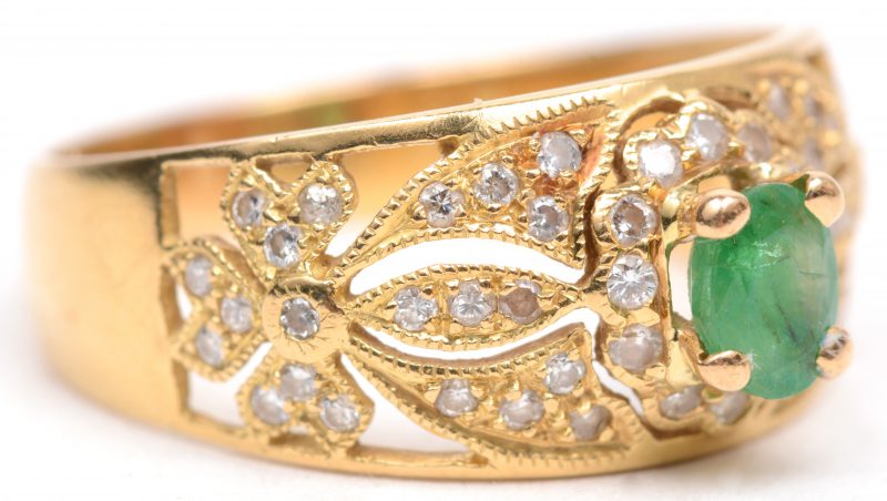 Een 18 karaats geel gouden ring bezet met briljanten met een gezamenlijk gewicht van +/- 0,50 ct. en een centrale smaragd van +/- 0,30 ct.
