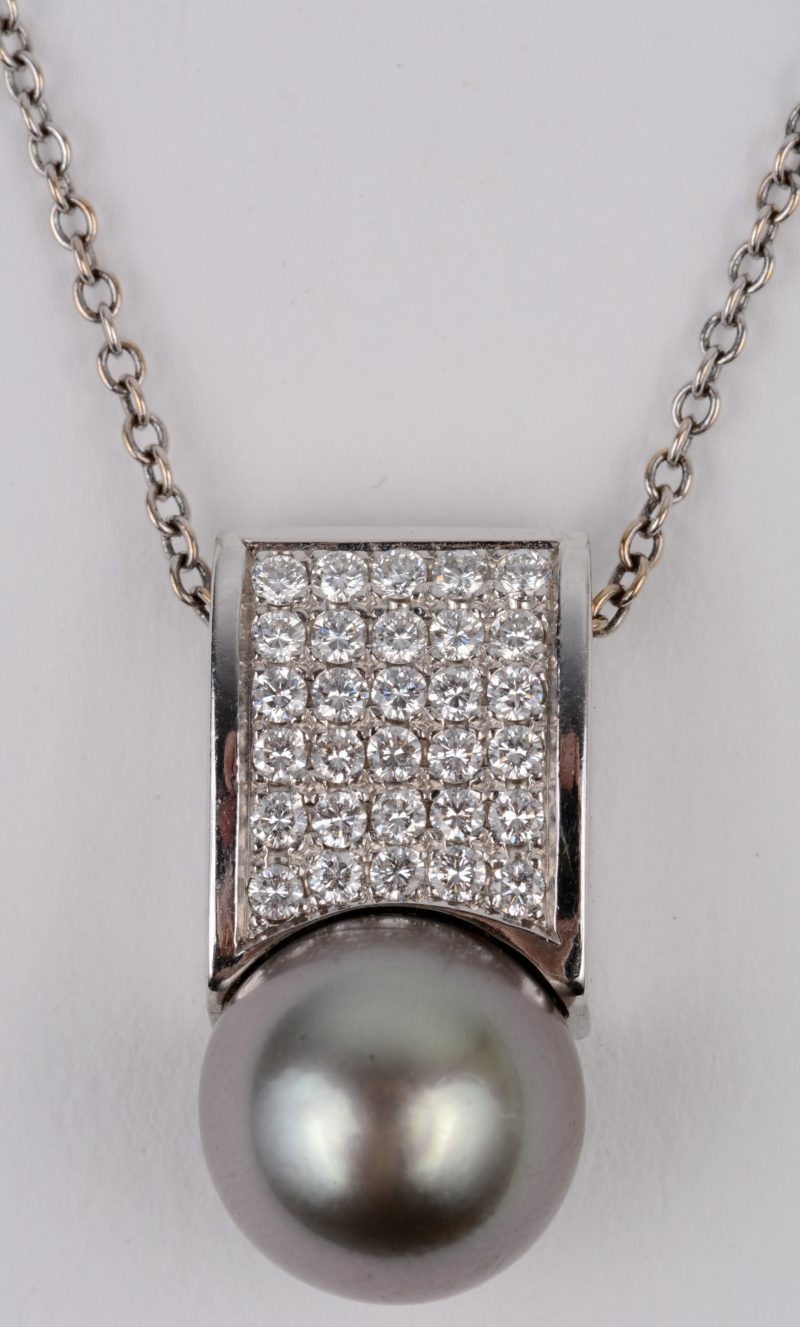 Een 18 karaats wit gouden ketting met hanger bezet met briljanten met een gezamenlijk gewicht van ± 0,45 ct. en een grijze parel.