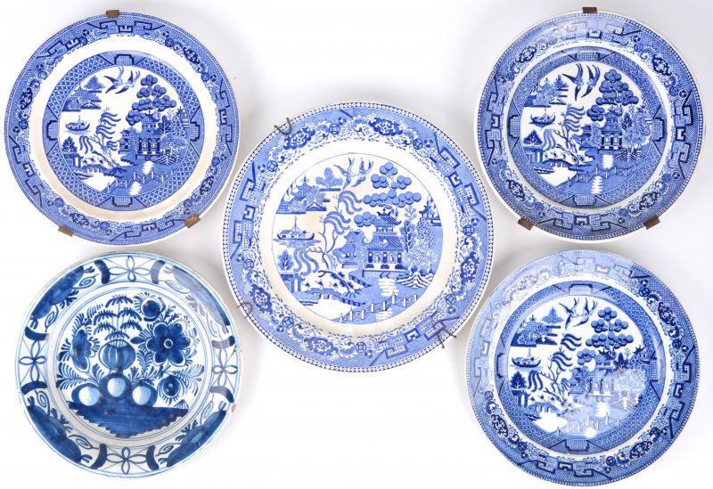 Een groot en drie kleinere borden van blauw en wit aardewerk met een ‘old willow’ decor. We voegen er een aardewerken bord met blauw en wit bloemendecor aan toe.