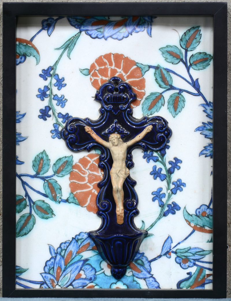 Een geglazuurd aardewerken wijwatervat in de vorm van Christus aan het kruis.