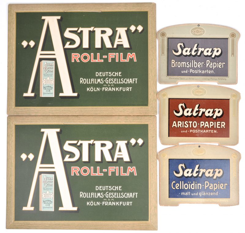 Een lot van vijf oude kartonnen reclameplaten, waarbij twee van ‘Astra roll-film’ en drie van ‘Satrap’.