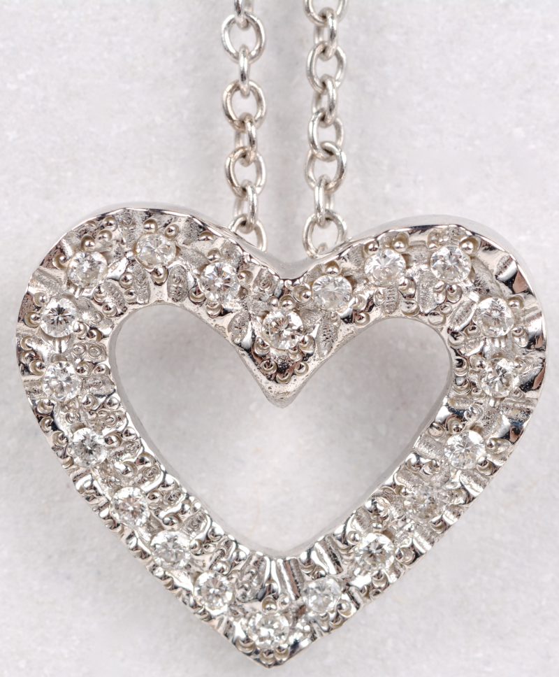 Een 18 karaats wit gouden ketting met hanger in de vorm van een hartje bezet met diamanten met een gezamenlijk gewicht van ± 0,20 ct.