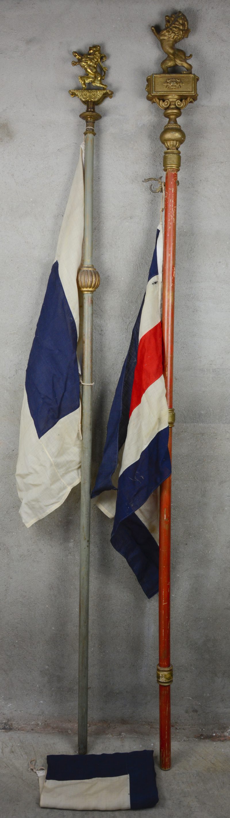 Twee verschillende vlaggenstokken, bovenaan getooid met een leeuw.