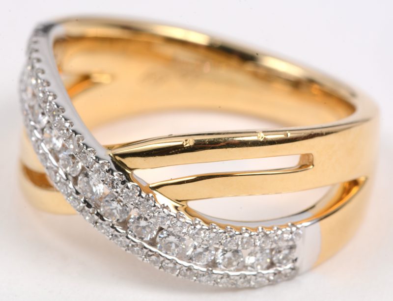 Een 18 karaats wit en geel gouden ring bezet met briljanten met een gezamenlijk gewicht van +- 0,58 ct.
