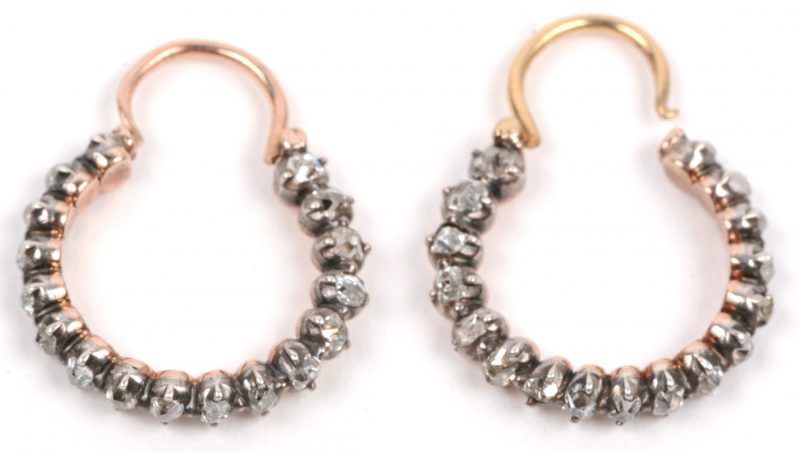 Een paar 18 karaats geel gouden oorbellen bezet diamanten oude slijp in zilver gezet met een gezamenlijk gewicht van +- 1,10 ct. (één steentje ontbreekt).