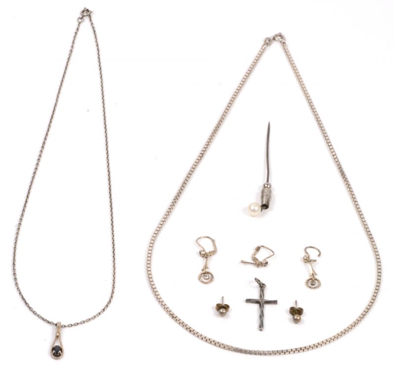 Een lotje zilver waaronder twee paar oorbellen, twee kettingen waarvan één met hanger, een kruisje en een speld.