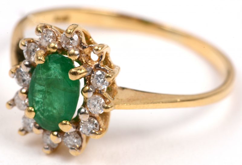 Een 18 karaats geel gouden ring bezet met één centrale smaragd van +- 0,40 ct. en met briljantjes met een gezamenlijk gewicht van +- 0,11 ct. (één steentje ontbreekt).