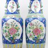 Een paar vazen van Chinees porselein met een decor van pioenen in cartouches met erond een vruchten op een blauwe achtergrond. Onderaan gemerkt.