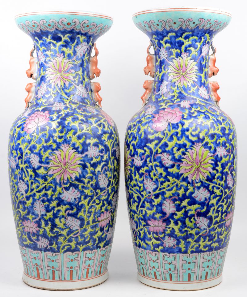 Een paar vazen van Chinees porselein met een famille-rosedecor van bloemen op een blauwe achtergrond. Onderaan gemerkt.