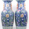 Een paar vazen van Chinees porselein met een famille-rosedecor van bloemen op een blauwe achtergrond. Onderaan gemerkt.