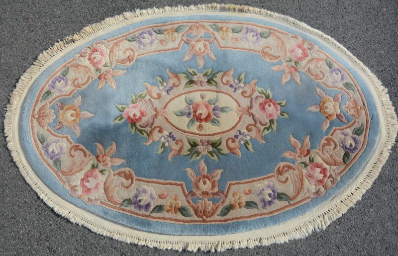 Een handgeknoopt ovaal Chinees wollen tapijt.