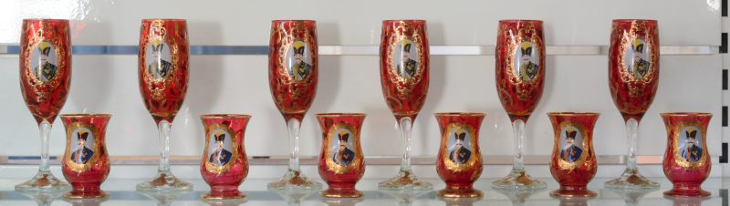 Een reeks van zes lage glaasjes en zes fluitglazen van rood glas met verguld decor.