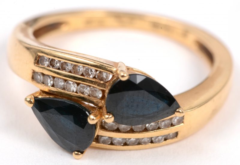 Een 18 karaats geel gouden ring bezet met diamanten met een gezamenlijk gewicht van +- 0,24 ct. en twee saffieren met een gezamenlijk gewicht van +- 1ct.