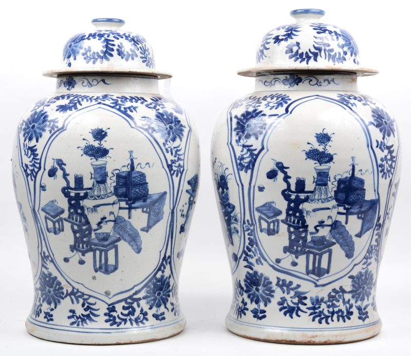 Een paar dekselvazen van Chinees porselein met een blauw op wit decor van kostbaarheden.