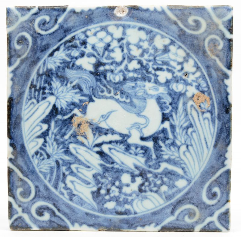 Een tegel van Chinees porselein met een blauw op wit decor van een fabeldier.