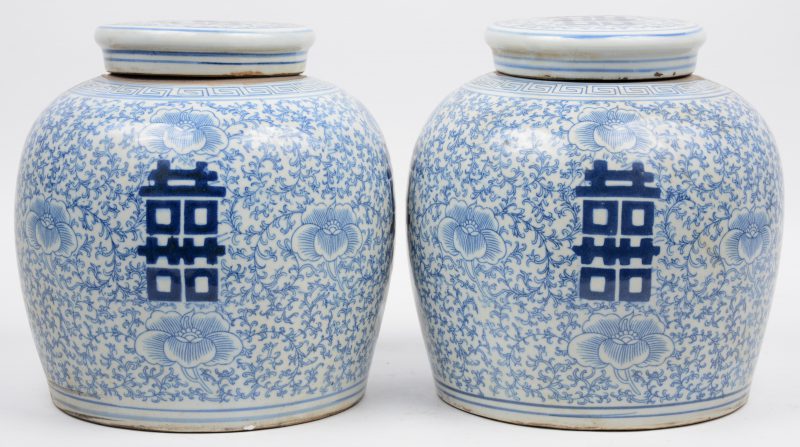 Een paar gemberpotten van chinees porselein met een blauw op wit floraal decor met gelukstekens.