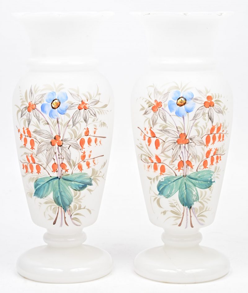 Een paar vazen van wit opaalglas met een handgeschilderd bloemendecor.