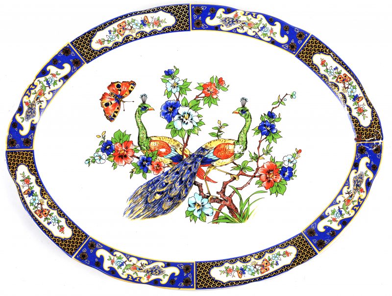 Een ovale schotel met een meerkleurig dedor van bloemen, pauwen en vlinders.