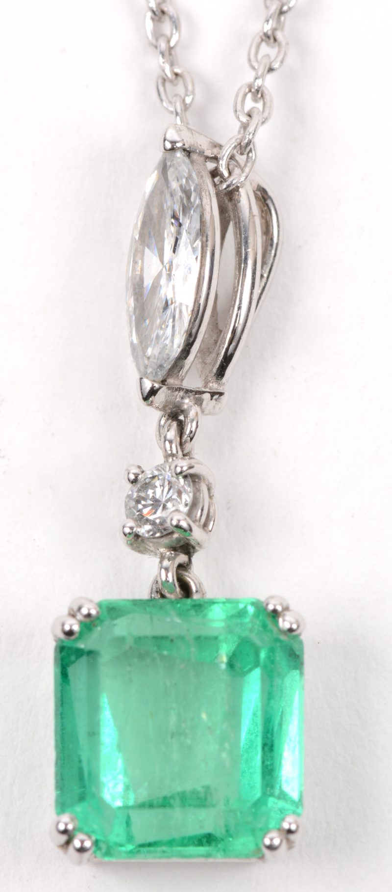 Een 18 karaats wit gouden ketting met hanger bezet met een in markies geslepen diamant en een briljant met een gezamenlijk gewicht van +- 0,60 ct. en een smaragd van +- 3 ct.