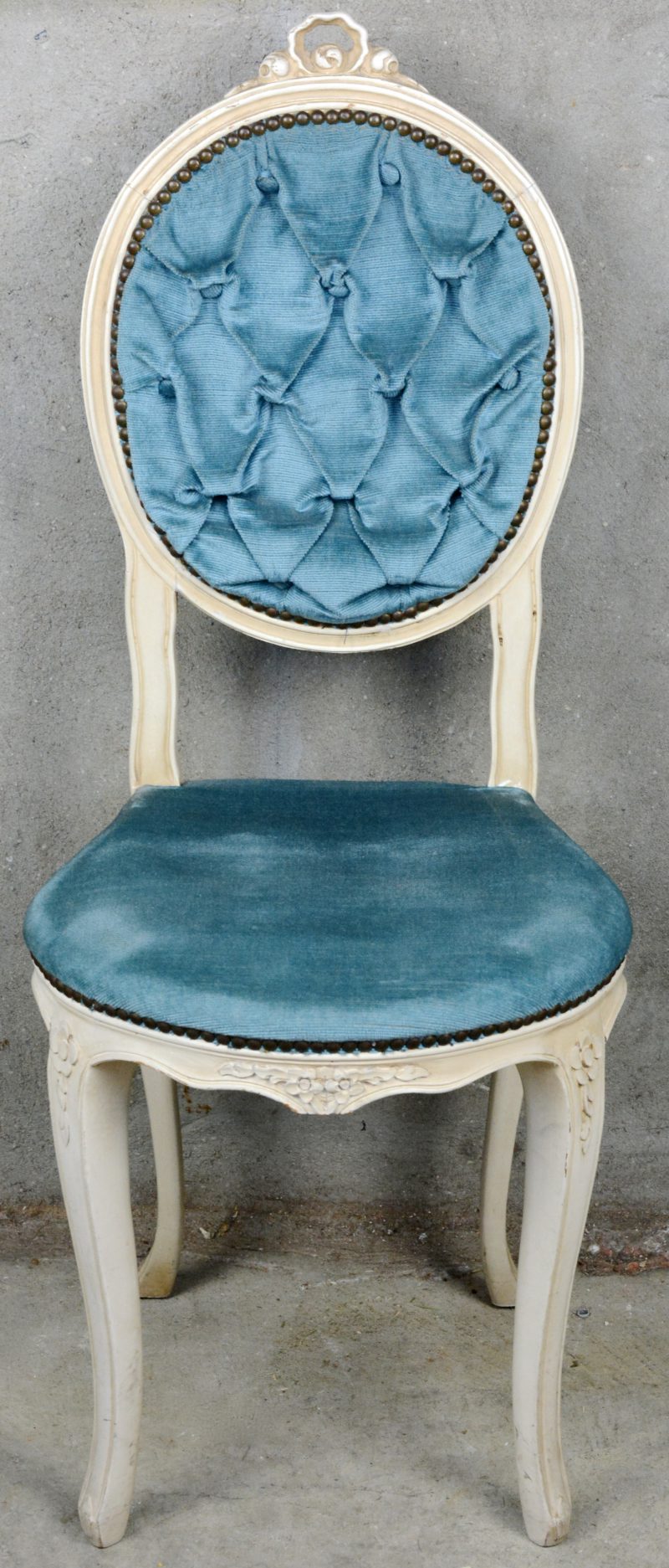 Een witgepatineerd boudoirstoeltje met blauw fluwelen bekleding.