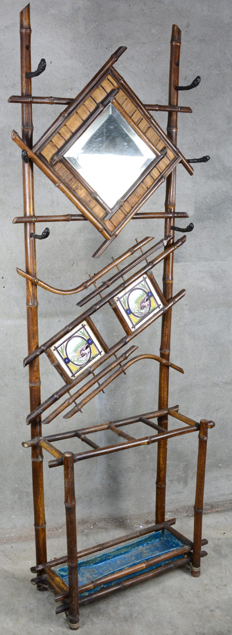 Een bamboe kapstok met spiegel en twee Franse tegeltjes.
