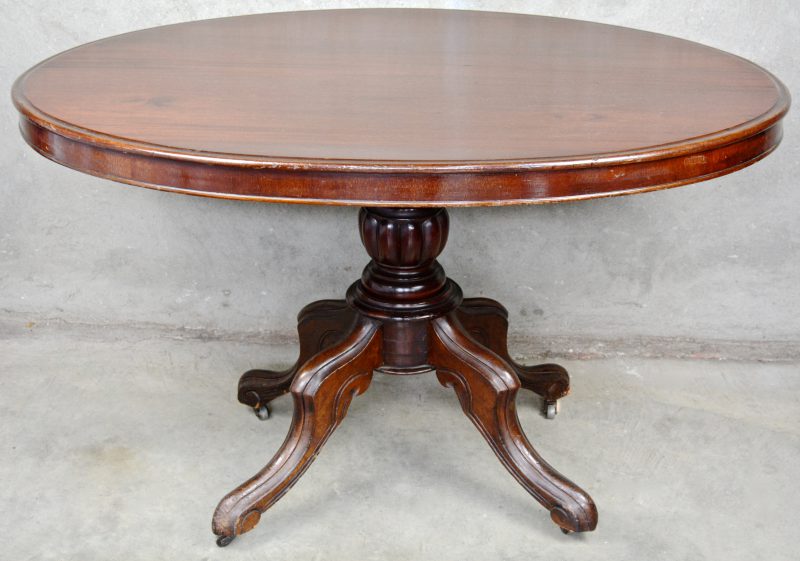 Een ovale tafel met kantelbaar blad en op wieltjes.
