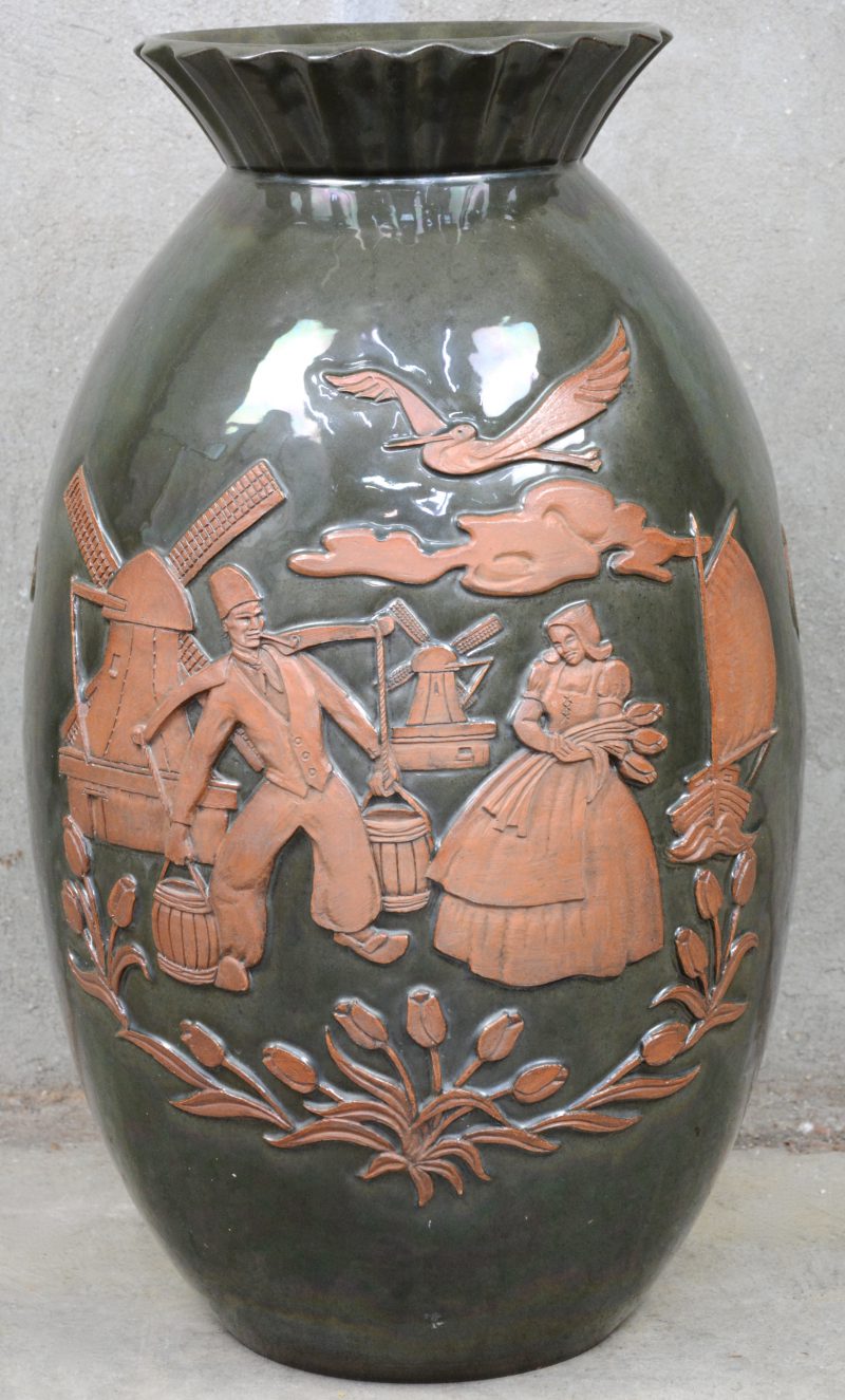 Een geëmailleerde terracotta vaas met een aziatisch en Hollands reliëfdecor. Onderaan gemerkt en gedateerd 10-2-1948.