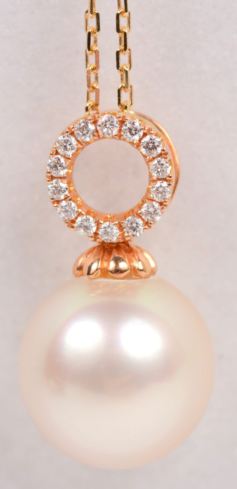 Een 18 karaats roze gouden ketting met roze gouden hanger bezet met briljanten met een gezamenlijk gewicht van +- 0,10 ct. en een parel. Met certificaat.