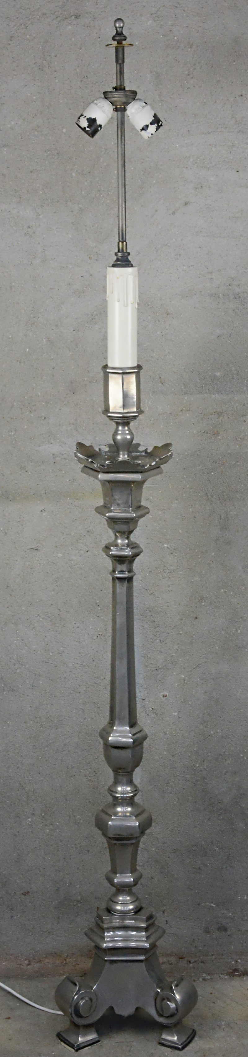Een grote metalen kandelaar, gemonteerd als staande lamp.