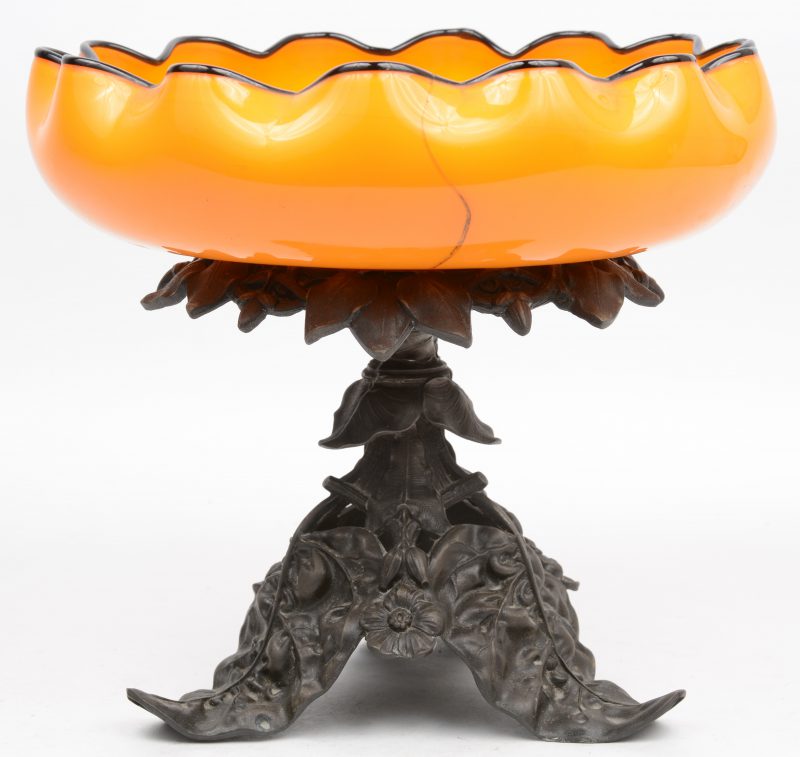 Een siercoupe van oranje glas op een zamakken voet in de vorm van bladeren en bloemen. Coupe gebarsten. Begin XXe eeuw.